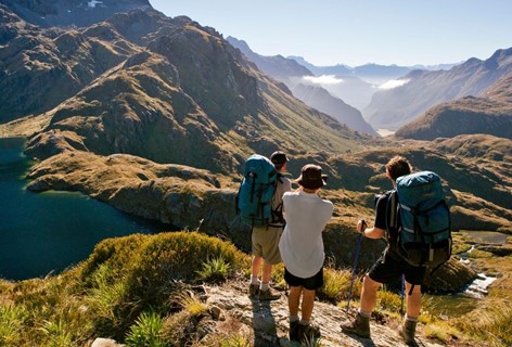 Three hikers look over the valley atop on the Routeburn Track, Milford Sound.