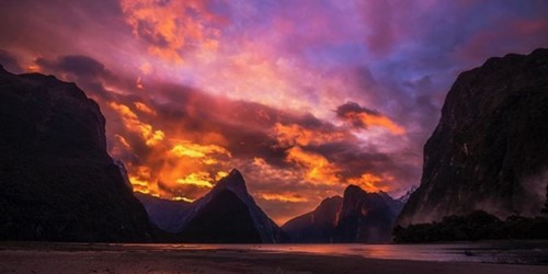 Sunset over the Milford Sound between the peaks, showing an incredible display of colour.