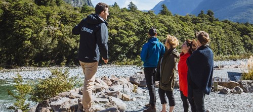 A Milford Sound Lodge tour guide explains the area's geography to a private tour group.