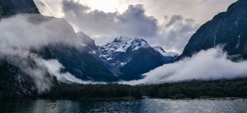 Low hanging clouds over Milford Sound with a dusting of snow on the peaks.