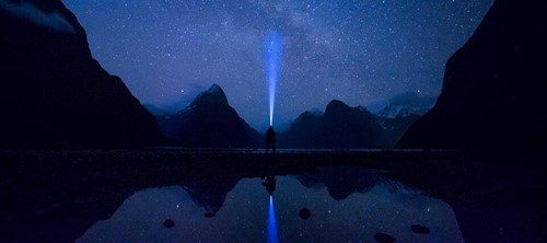 The night skies in the Milford Sound filled with stars, reflected in the sound.