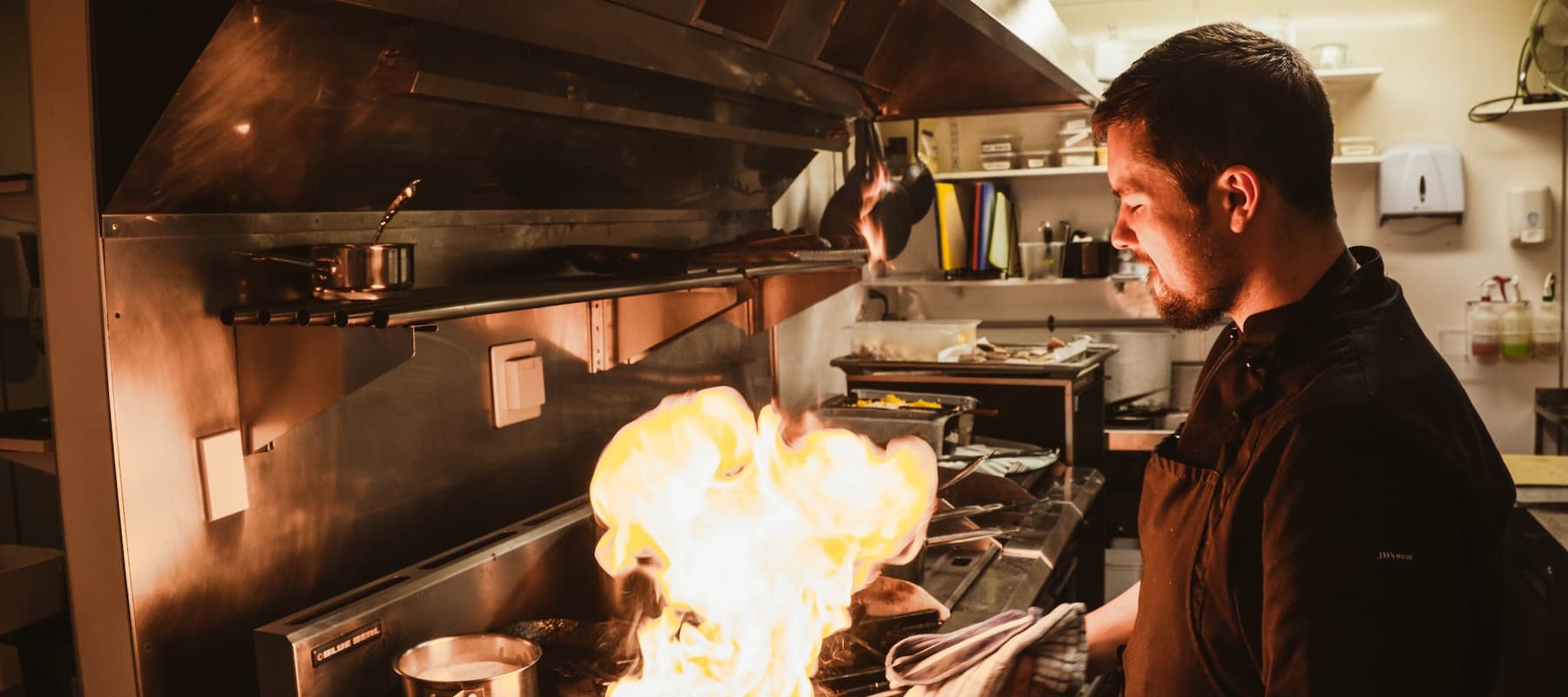 Happy Chef cooking with flames in the kitchen at Pio Pio Restaurant Milford Sound
