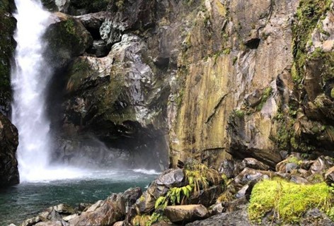 A waterfall naturally caved through cliff faces on the Hollyford Track in Milford Sound.